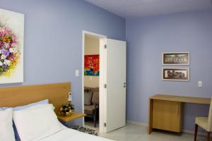 a bedroom with blue walls and a bed and a desk at Solar da Lorena in Florianópolis
