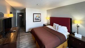a hotel room with a bed and a flat screen tv at Magnuson Hotel Fort Wayne North - Coliseum in Fort Wayne