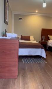 a bedroom with a bed and a wooden dresser at Hotel Vista Verde in Huancayo