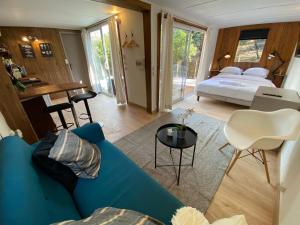 uma sala de estar com um sofá azul e uma cama em Superbe Cabane JACUZZI JARDIN CLIM WIFI PARKING em Meyreuil