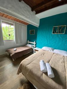 a bedroom with two beds and a blue wall at Pousada Casa Mato in Taubaté