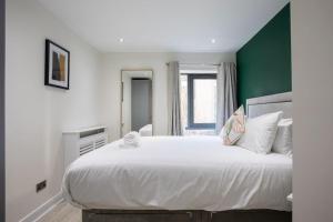 a bedroom with a large white bed with a green wall at Luxury, Sleeps 6, City Centre in Belfast