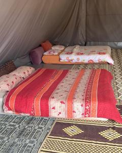 two beds sitting inside of a tent at חאן בכפר במשק בלה מאיה - האוהל in Nevatim