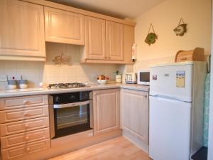 a kitchen with white appliances and wooden cabinets at Mead Cottage in Bridport