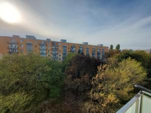 ein Apartmenthaus im Hintergrund mit Bäumen im Vordergrund in der Unterkunft Apartmán Merry (9) in Bratislava