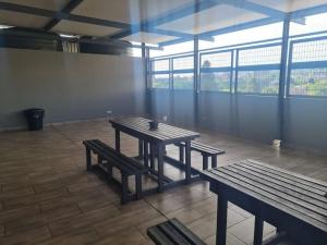 a table and benches in a room with windows at Stunning City Living at Loftus in Pretoria