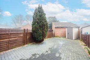a large tree in a yard next to a fence at Lovely 2 Bed House in Grays. in Grays Thurrock