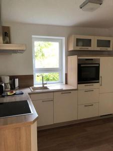 a kitchen with white cabinets and a window and a sink at Ferienhaus-Wiesenblick in Gammendorf