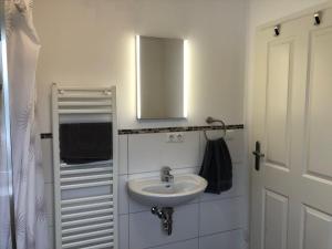 a white bathroom with a sink and a mirror at Ferienhaus-Wiesenblick in Gammendorf