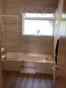 a bathroom with a bath tub and a window at Moriston Cottage in Lochcarron