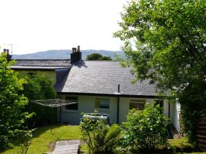 a house with a gray roof and a yard at Moriston Cottage in Lochcarron