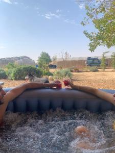 Ein Mann in einer Badewanne mit Armen im Wasser. in der Unterkunft חאן בכפר במשק בלה מאיה - האוהל in Nevatim