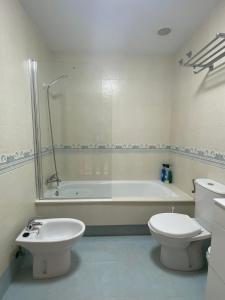 ein Badezimmer mit Badewanne, Toilette und Waschbecken in der Unterkunft Chalet Portosin con piscina al lado de la playa in Goyanes