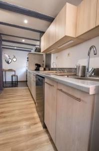 a kitchen with stainless steel appliances and a wooden floor at Le nid cosy d'Obernai /2min centre ville/parking in Obernai