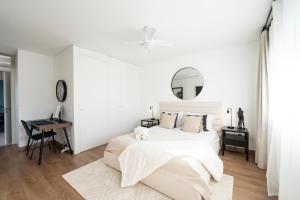 een witte slaapkamer met een bed en een bureau bij Mar a Vista - Condominium with Pool, Gym and Sea Views in Nazaré