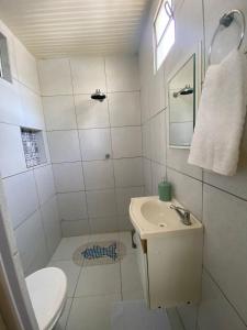 a white bathroom with a toilet and a sink at Beach House Peroba in Maragogi