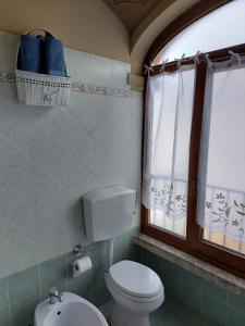 La salle de bains est pourvue de toilettes, d'un lavabo et d'une fenêtre. dans l'établissement Casa San Rocco, à Chiusa di Pesio