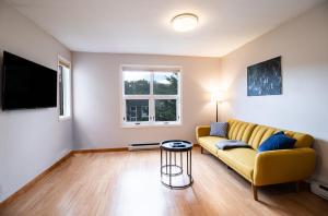 ein Wohnzimmer mit einem gelben Sofa und einem Tisch in der Unterkunft NN - Pink Palace - Downtown 1-bed 1-bath in Whitehorse