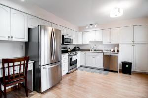 uma cozinha com armários brancos e um frigorífico de aço inoxidável em NN - Pink Palace - Downtown 1-bed 1-bath em Whitehorse