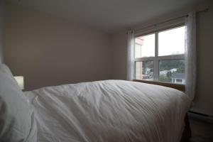 uma cama branca num quarto com uma janela em NN - Pink Palace - Downtown 1-bed 1-bath em Whitehorse