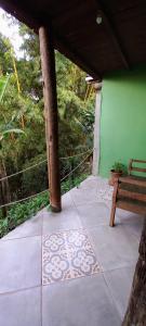 a patio with a bench and a green wall at Pousada Casa Mato in Taubaté