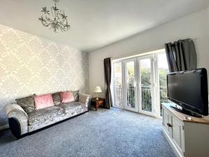 a living room with a couch and a flat screen tv at Angel Lane Alnwick Apartment in Alnwick