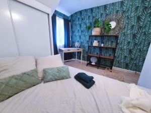 um quarto com uma cama branca e uma parede verde em Bel appartement à 3 min de la plage de 60m² em Saint-Nazaire