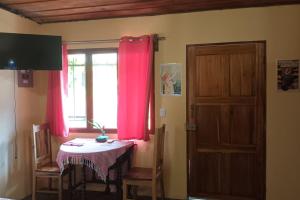 Cette chambre dispose d'une table et d'une fenêtre avec des rideaux roses. dans l'établissement Casita Olivia, à Sámara