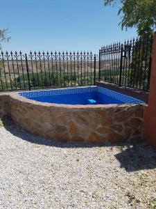 a swimming pool with a stone wall and a fence at Cueva Maite in Cortes de Baza