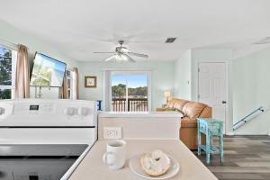 a kitchen with a white stove top oven next to a living room at Beachside Serenity Escape - Private 3BR and 2BA, DOG FRIENDLY Duplex Oasis, Steps to Shore! in Melbourne