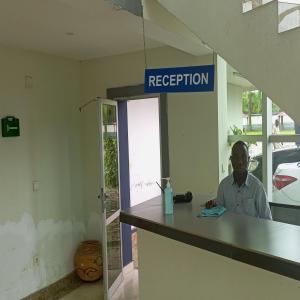 a man sitting at a reception desk in a room at Paradise Appartment hotel in Mutumba