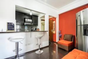 a kitchen with an orange accent wall and a refrigerator at MINI APARTAMENTO, Netflix, Disney Plus, sector privilegiado, cerca de todo in Quito