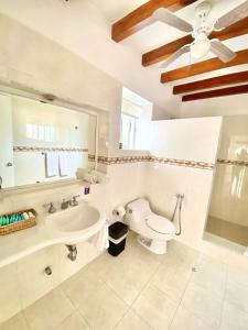 a white bathroom with a toilet and a sink at Hostería del Parque in Machalilla