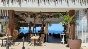 un restaurante con mesas, macetas y el océano en EL BOBO BEACH- Deluxe 2 bedroom apartment, en Playa Fañabe