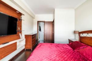 1 dormitorio con cama roja y TV de pantalla plana en MINI APARTAMENTO, Netflix, Disney Plus, sector privilegiado, cerca de todo, en Quito