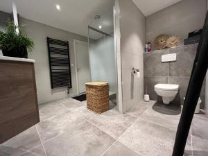 een badkamer met een toilet en een glazen douche bij Guesthouse BedNboot met terras aan het water in Rijpwetering