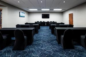 una sala de conferencias con mesas y sillas negras en Endeavor Inn & Suites, Trademark Collection by Wyndham, en Topeka