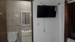 a bathroom with a toilet and a television on the wall at Alojamiento Guemes in Gualeguay