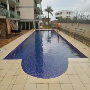 a man standing in front of a swimming pool at Paradise Appartment hotel in Mutumba