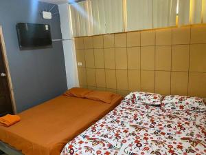 a room with two beds and a tv on the wall at Dpto en Grazota Norte de Guayaquil in Guayaquil