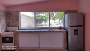 a kitchen with a sink and a refrigerator and a window at LA CHOZITA DEL MAR in Celestún