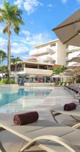 einem Pool mit zwei Liegestühlen und einem Gebäude in der Unterkunft Dreams Aventuras Riviera Maya - All Inclusive in Puerto Aventuras
