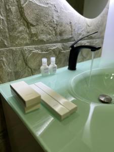 eine Badezimmertheke mit einem Waschbecken und zwei Seifenflaschen in der Unterkunft TD’s place in Okinni