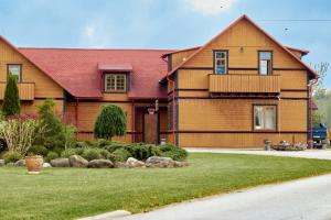 a large wooden house with a red roof at Juku Dzirnavas in Zutēni