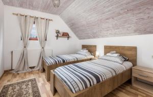 two beds in a bedroom with wooden ceilings at Angel Holiday House in Ravna Gora