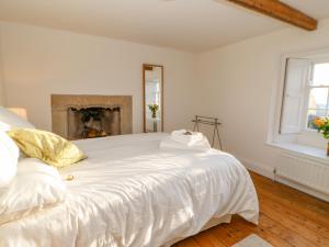 a bedroom with a large white bed with a fireplace at East Farm House in Humshaugh