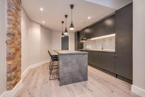 a kitchen with black cabinets and a bar with stools at Castle Buildings in Belfast