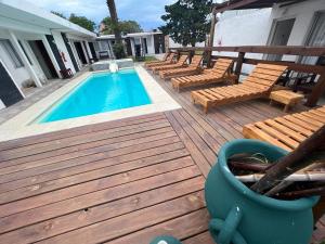 a wooden deck with a swimming pool and some chairs at Gran Colonial Riviera in Piriápolis