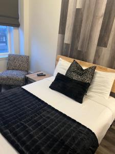 a bedroom with a bed with black pillows and a chair at Commercial Hotel in Edmonton