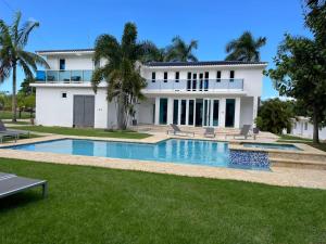 a large white house with a swimming pool in front of it at Manati World Point Inn in Manati